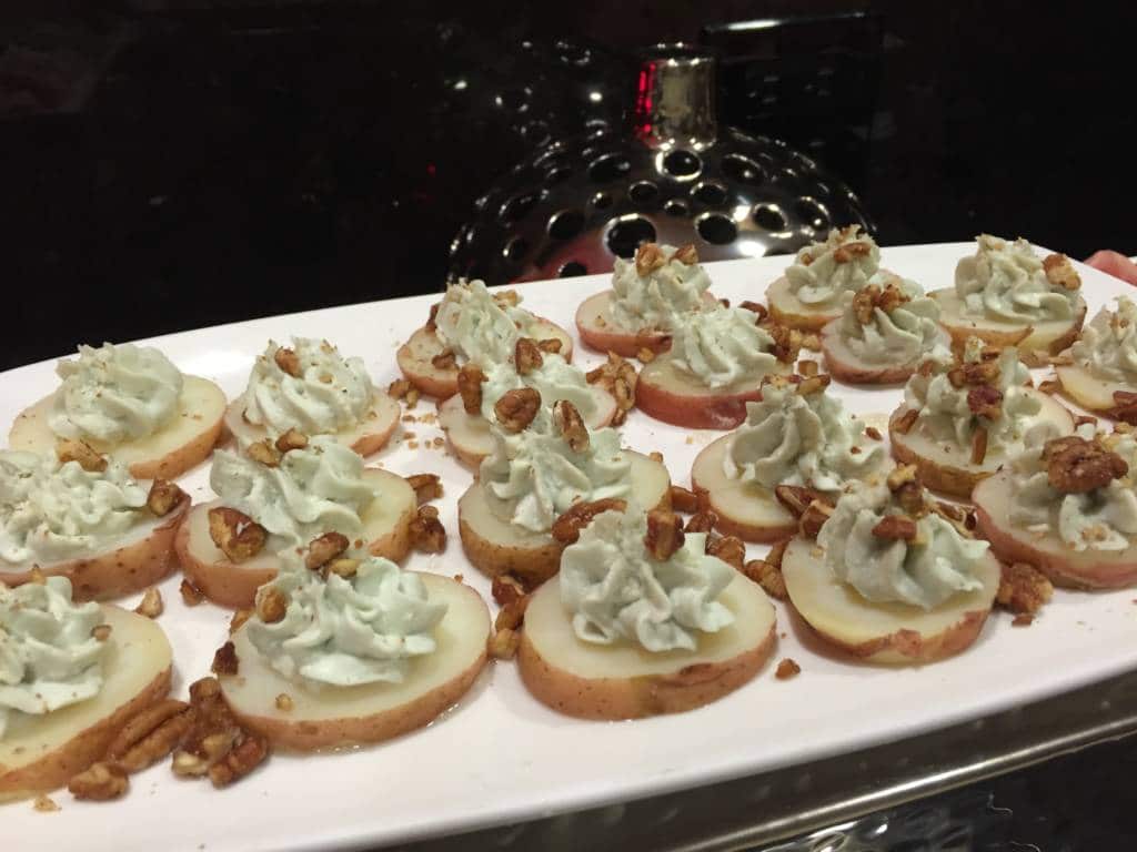 A platter of potato slices topped with cream and nuts