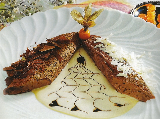 A dessert with sauce and shaved dark and white chocolate